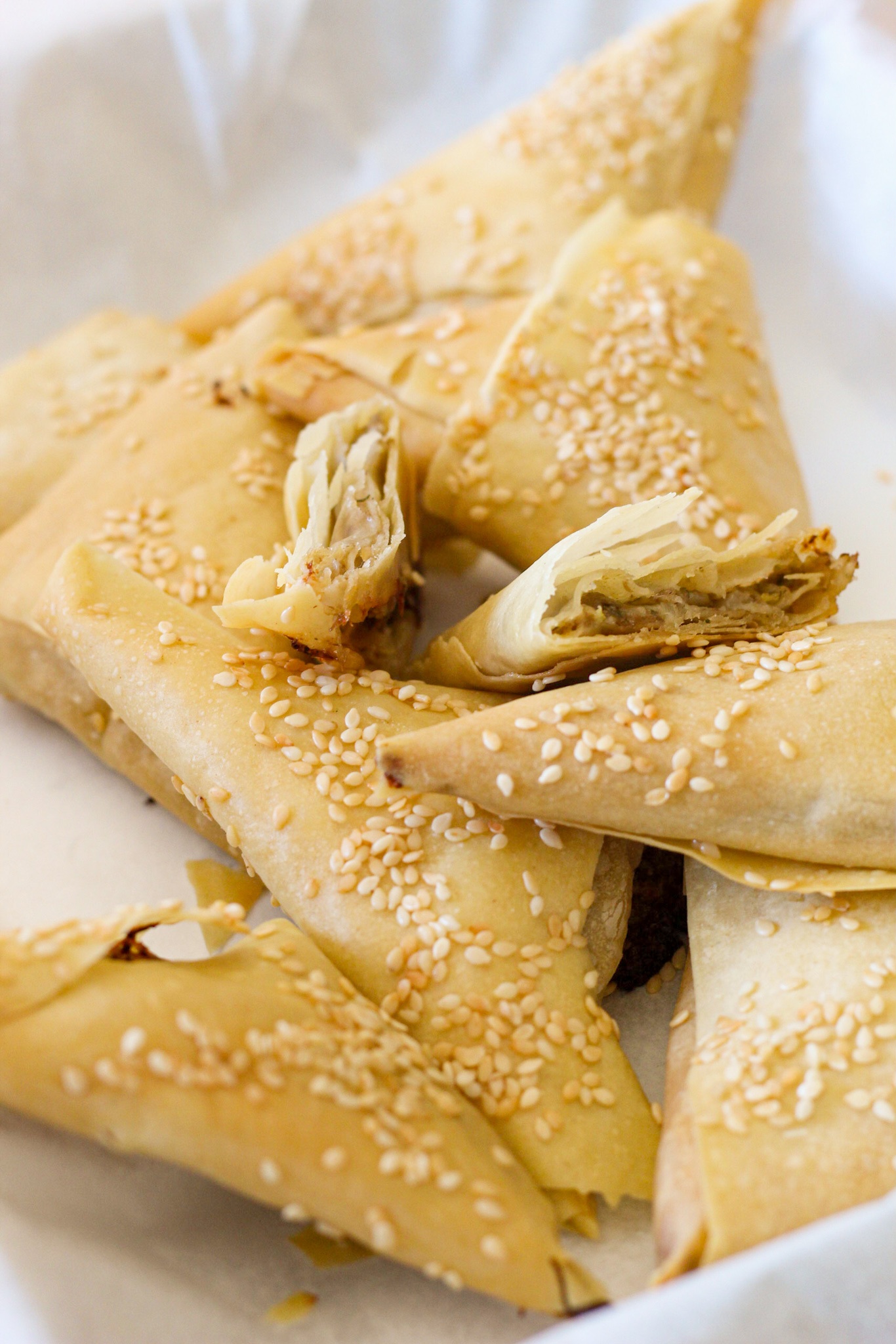 Triagled pastry puffs topped with sesame seeds and filled with mushrooms and cheeses